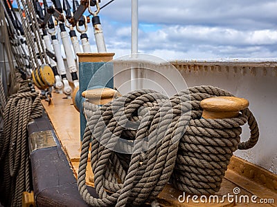 Traditional wooden cleatÂ and coiled ropes on US tallship Eagle Stock Photo